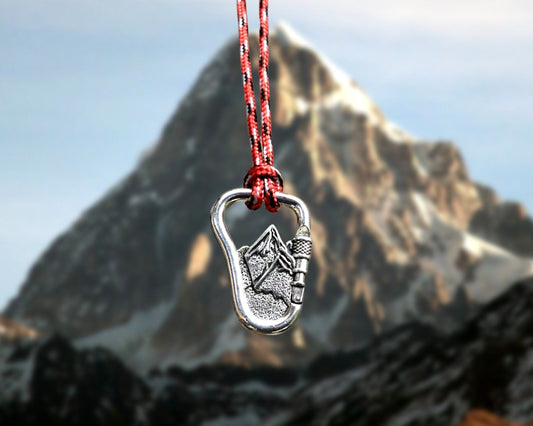 Silver carabiner with a mountain design on a red cord against a mountainous background