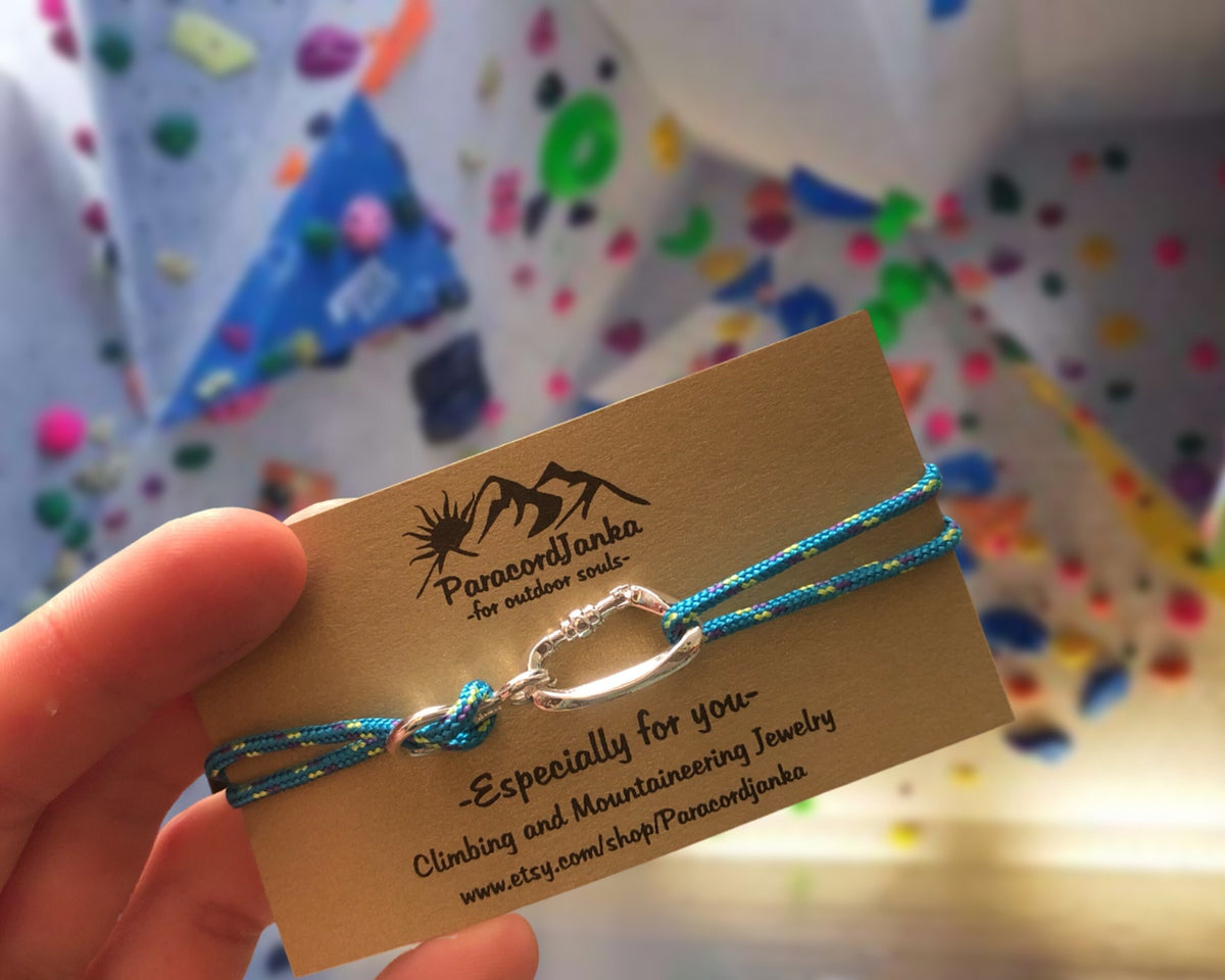 Blue climbing bracelet on a card held by a hand with a colorful background