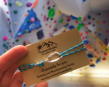 Blue climbing bracelet on a card held by a hand with a colorful background