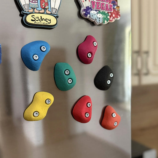 Colorful rock-shaped magnets on a refrigerator with a blurred kitchen background