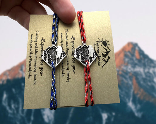 Two braided bracelets with mountain designs on a card with text and branding, against a mountainous background.