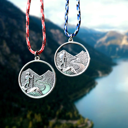 Two silver necklaces with pendant designs against a blurred natural background