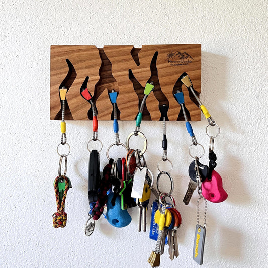Wooden key holder with multiple keys hanging on it against a white wall