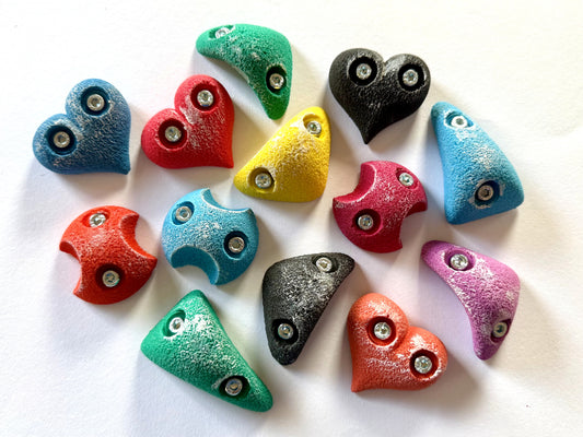 A set of colorful, uniquely shaped decorative heart-shaped beads with silver metal eyelets, displayed on a plain white background.