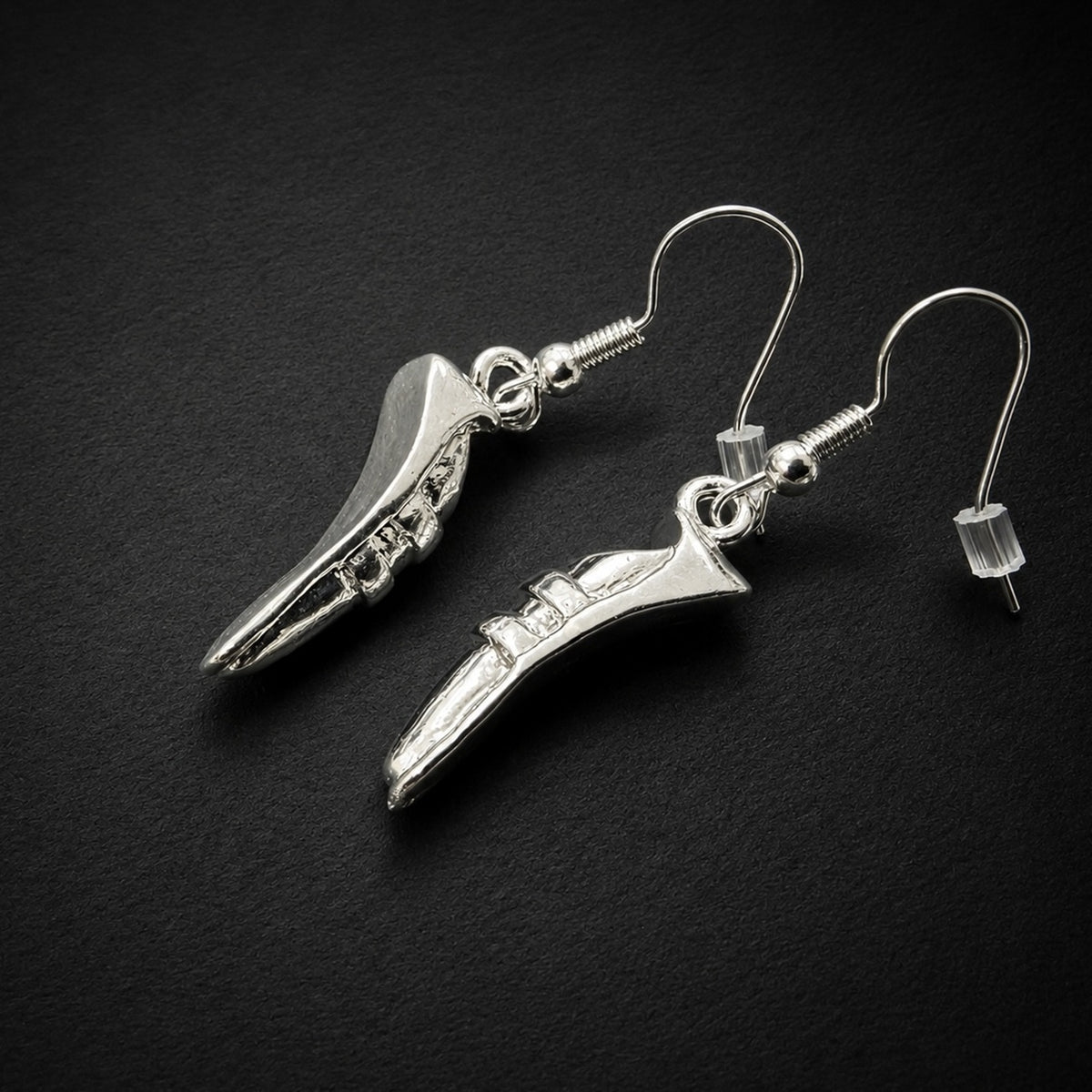 A pair of silver dangling earrings shaped like miniature ice skates, displayed on a dark textured background.