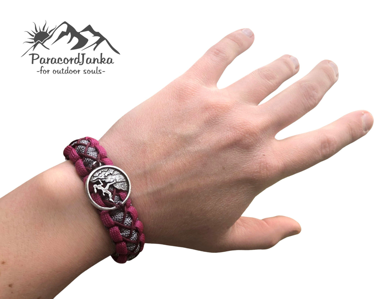 Hand wearing a purple braided bracelet with a silver tree of life charm, branded 'Parasontenka'.