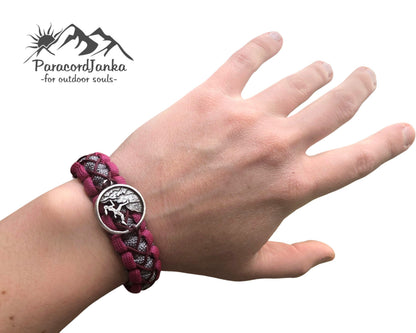 Hand wearing a purple braided bracelet with a silver tree of life charm, branded 'Parasontenka'.