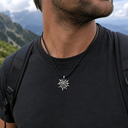 A man wearing an Edelweiss Mountain Necklace Gift for Hiker outdoors with mountain peaks behind him.