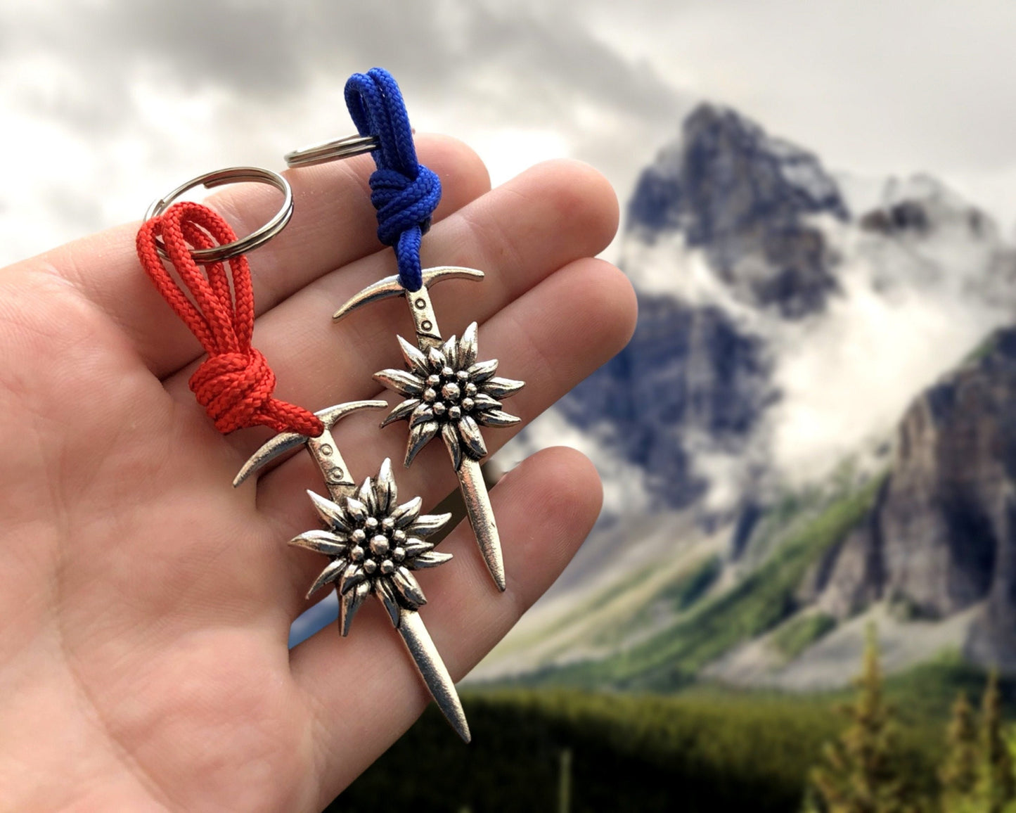 May include: Two silver keychains with a sword design and a flower charm. The keychains are attached to red and blue cords.