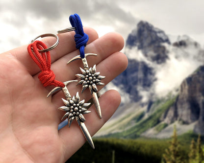 May include: Two silver keychains with a sword design and a flower charm. The keychains are attached to red and blue cords.